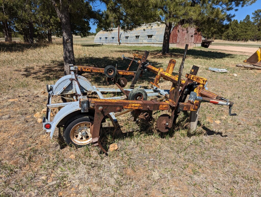 Rusty yellow mulch laying machine on a gray towing trailer